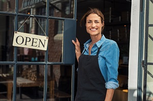 business owner standing outside business with open sign