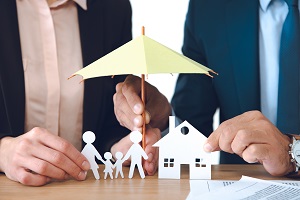 two insurance agents holding paper family under paper umbrella
